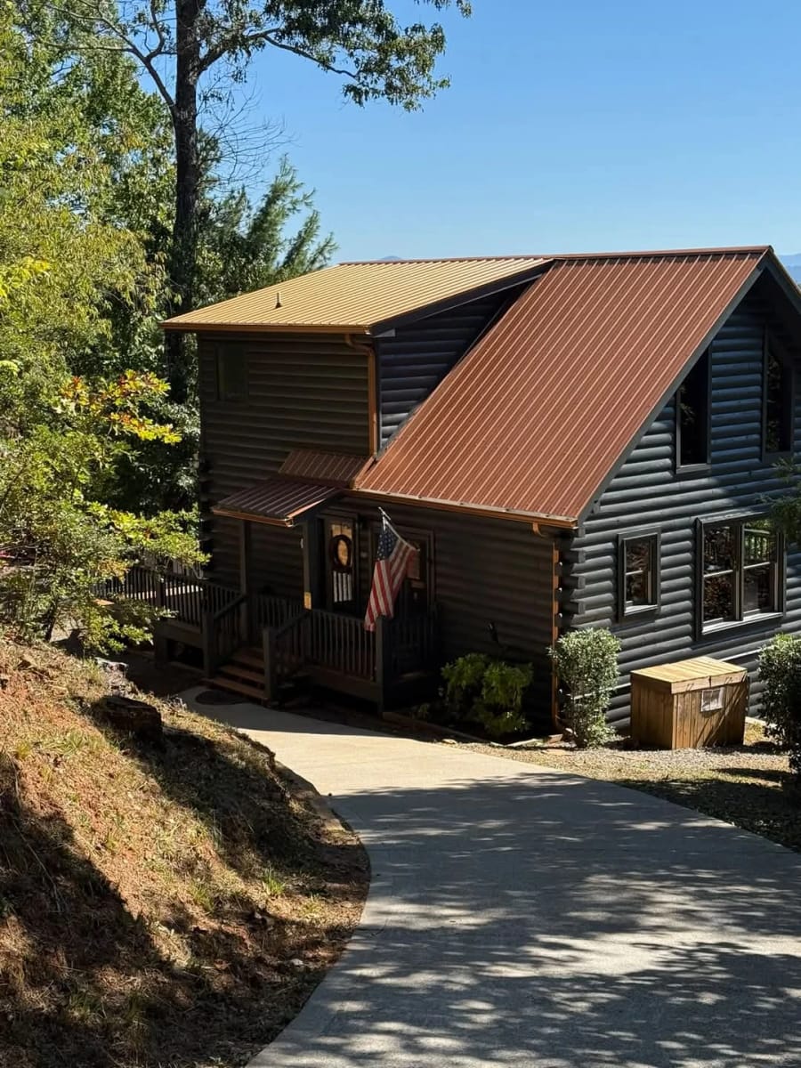 Log cabin home with a metal roof, tidy driveway and clean exterior